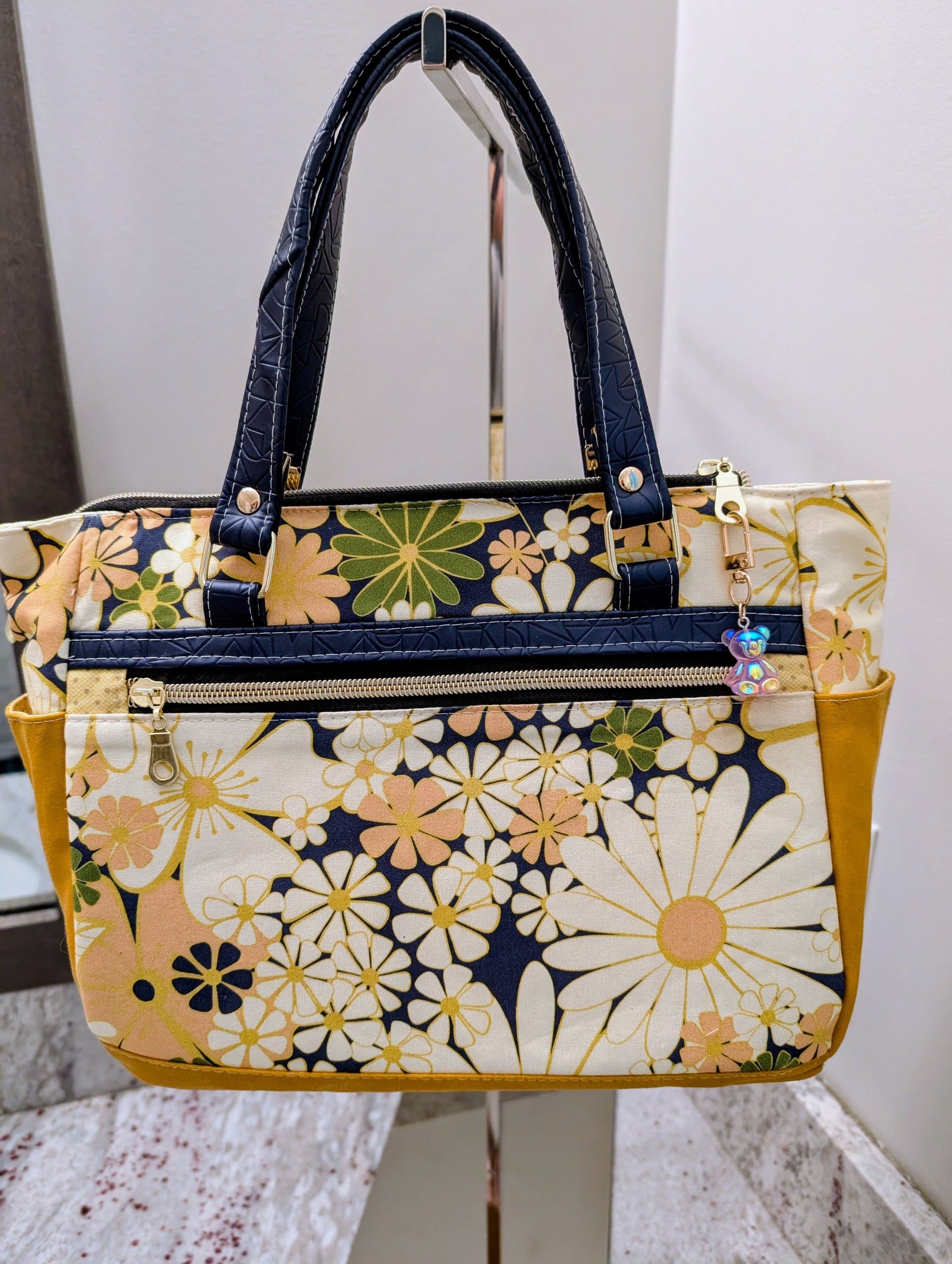 Floral patterned handbag on a stand with a white background